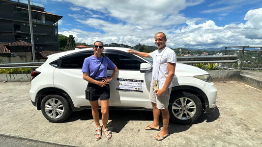 Two people standing next to a white SUV with a visible brand logo on a sunny day.