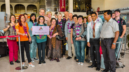 A group of people standing together for a group photo, likely tourists at a travel agency or airport