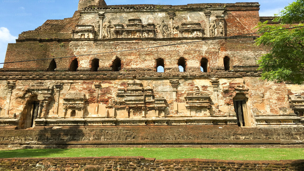 An ancient architectural site with visible ruins and a backdrop of a large, natural wall.