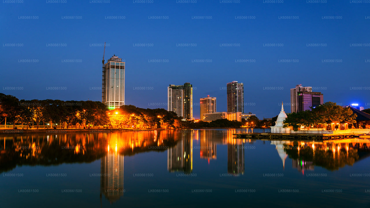 A panoramic view of Colombo cityscape at dusk, featuring a blend of colonial and modern buildings alongside a body of water.